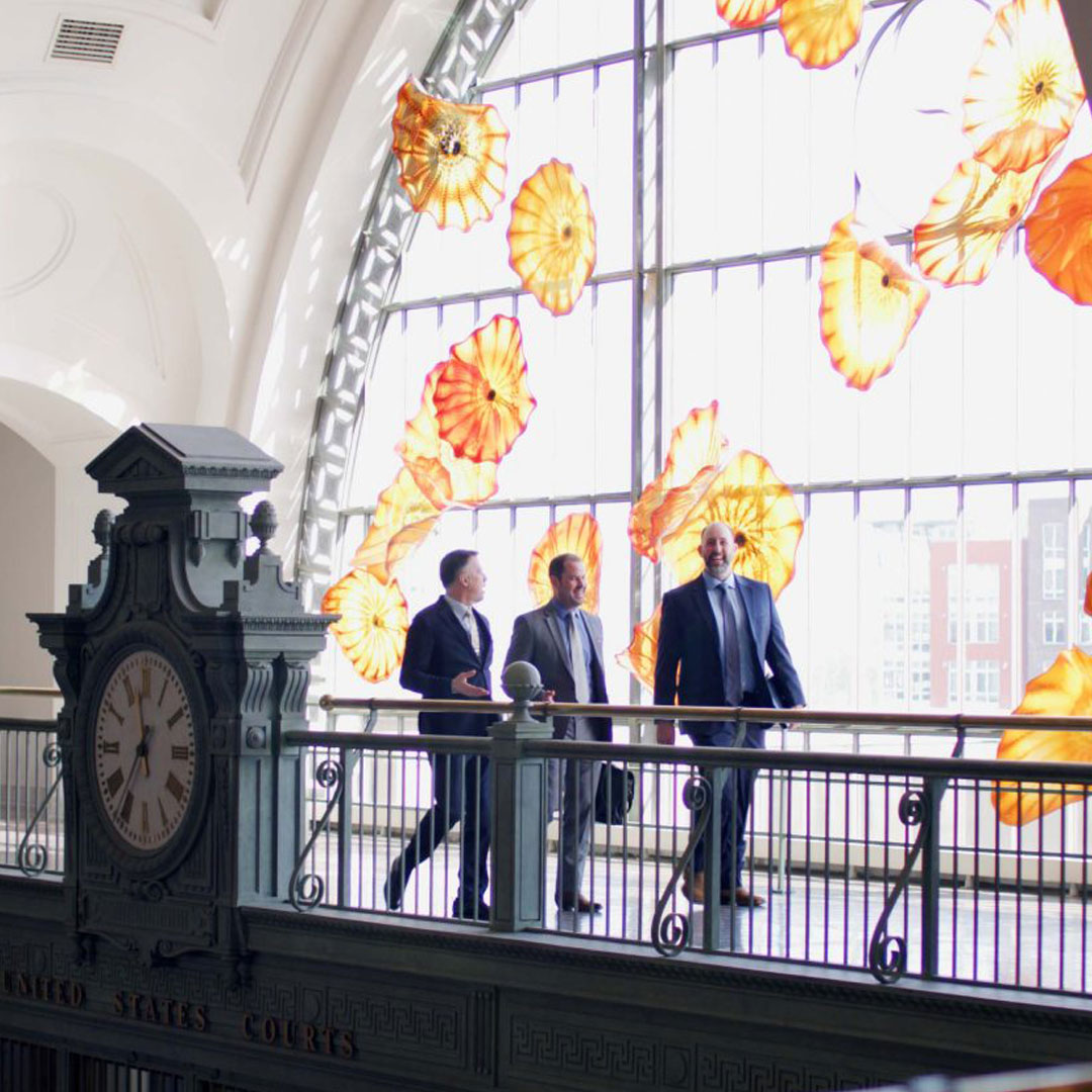 Three man wearing suit talking behind the clock